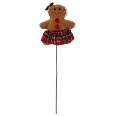 a brown teddy bear wearing a red and black plaid dress on a long stick with a bow in its hair