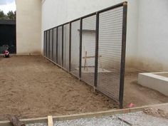 a fenced in area next to a building with a motorcycle parked on the ground