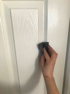 a person using a power drill to fix a door handle on a white door frame