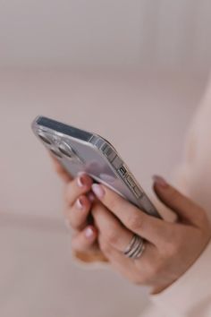 a close up of a person holding a cell phone in their hands and looking at the screen