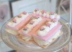 there are many small pieces of food on the glass platter with pink icing