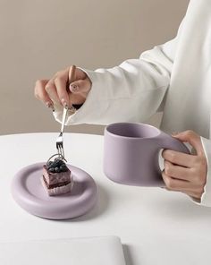 a woman is cutting into a piece of cake on a plate with a knife and fork