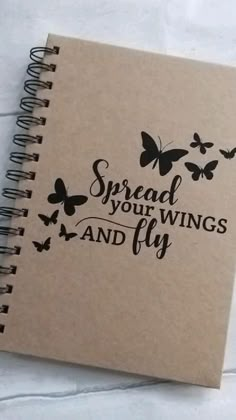 a spiral notebook with the words spread your wings and fly written in black on it