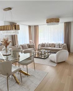 a living room filled with furniture and a chandelier above a glass top table