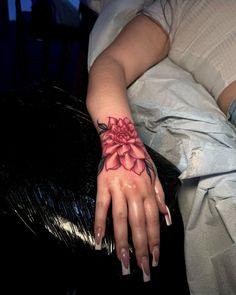 a woman's hand with a flower tattoo on it