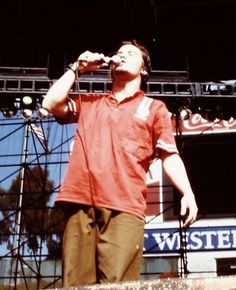 a man standing on top of a stage holding a microphone in his hand and singing