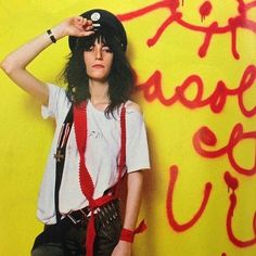 a woman standing in front of a yellow wall with graffiti on it's walls