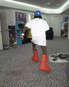 a man wearing orange boots and a blue hat is walking through a room with other items