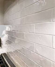 a stove top oven sitting next to a white tiled wall