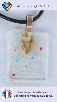 a glass pendant with confetti on it and the words art biloux ouel eclat