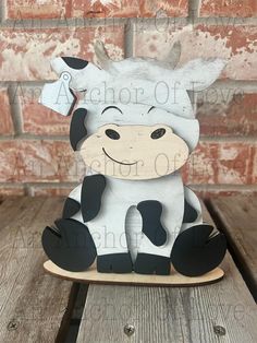 a cow sitting on top of a wooden sled next to a brick wall in the background