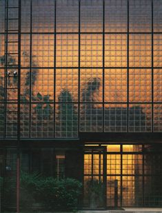 an image of the outside of a building at sunset or dawn with clouds reflected in the windows