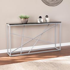 a modern console table with black marble top and silver metal frame, in front of a beige wall