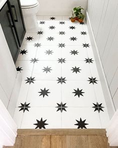 an image of a bathroom floor with black stars on the white tile and wood floors