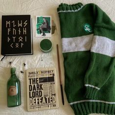 the contents of a green sweater laid out on top of a white sheet with writing