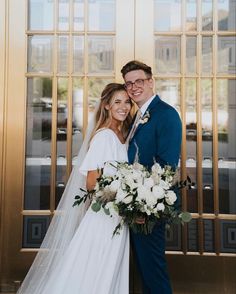 a bride and groom pose for a photo in front of the doors of their wedding venue