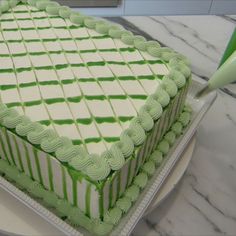 a green and white cake sitting on top of a counter next to a spatula