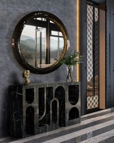 a large round mirror hanging on the side of a wall next to a black cabinet