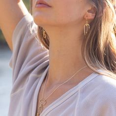 An archway of silver is textured by hand and surrounds a barrel of rutilated quartz. Beams of gold pass through these unique gemstones accenting the tiny gold links dropping from them. •Sterling Silver and 14k Gold Filled •Rutilated Quartz •Dimensions: 1/2 x 2"