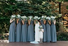 a group of women standing next to each other in front of some trees and bushes