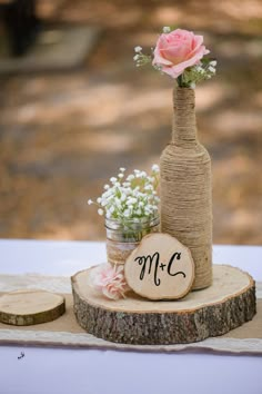 a wooden slice with flowers in it sitting on a table next to a wine bottle