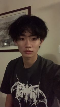 a young man with black hair wearing a t - shirt and looking at the camera