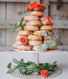 there are donuts stacked on top of each other with flowers in the middle and greenery around them