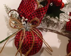 a red and black christmas ornament on a white plate next to holly branches