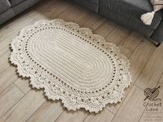 a white crocheted rug on the floor next to a couch