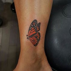 a small butterfly tattoo on the ankle, with an orange and black color scheme that matches the rest of the foot