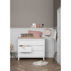 a white dresser with pink and brown pillows on top of it in a room that has wood flooring