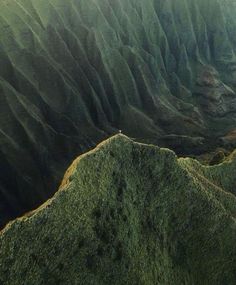 an aerial view of mountains and valleys in the distance with green grass growing on them