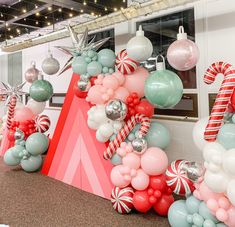 balloons and candy canes are arranged in the shape of a christmas tree on display