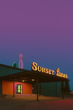 the neon sign for sunset lanes is lit up in front of an empty parking lot