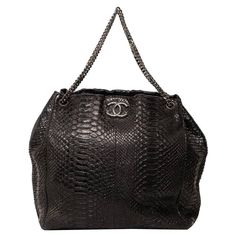 Borsa tote firmata Chanel, realizzata in pelle di pitone nero con hardware argentati. Dotata di una patta centrale con chiusura a bottone calamitato, internamente rivestita in tessuto grigio, molto capiente. Munita di una tracolla in catena a scorrimento, che permette di indossare la borsa a mano e a spalla. Presenta una tasca interna con chiusura a zip e un gancio. Anno di produzione 2008/09, l’articolo si presenta in ottime condizioni. Tote bag by Chanel, made of black python leather with silv Vintage Chanel Bag, Chanel Tote Bag, Black Python, Chanel Suit, Chanel Brand, Gabrielle Chanel, Chanel Tote, Beige Bag, Made Of