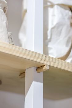 a bag is sitting on the edge of a wooden shelf in front of a white wall