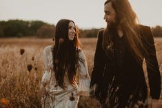 a man and woman are walking through the tall grass in front of each other with long hair