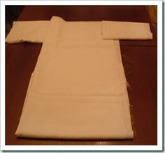 the folded white cloth is laying on top of the wooden table and ready to be sewn