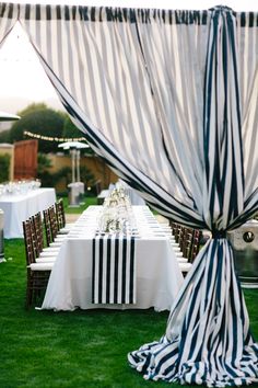 an outdoor table set up with black and white striped cloths