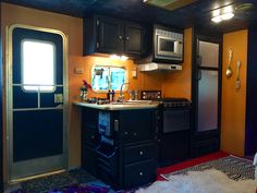 a kitchen with black cabinets and stainless steel appliances in an rv or trailer home that is brightly lit