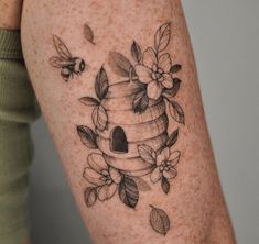 a woman's arm with a beehive and flowers tattoo design on it