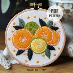 an embroidery pattern with oranges and green leaves on it, next to a potted plant