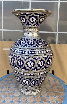 a large blue and white vase sitting on top of a table next to a tiled wall