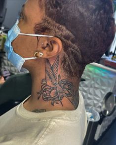 a woman with a bird tattoo on her neck and behind her ear, wearing a surgical mask