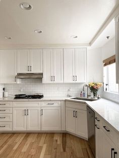 a kitchen with white cabinets and wood floors