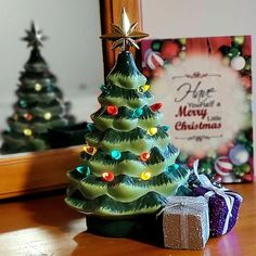 a small christmas tree sitting on top of a wooden table next to a gift box