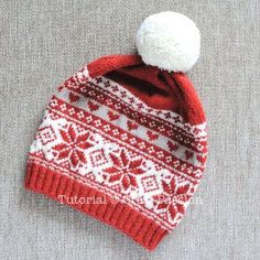 a red and white knitted hat with a pom - pom