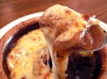 a close up of a plate of food with cheese and sauce on it, being held by a spoon