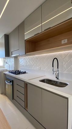 a modern kitchen with stainless steel appliances and white counter tops, along with wooden cabinets