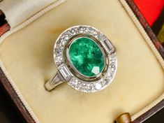 Grassy green and undertones of blue punctuate this vision of an Art Deco inspired diamond ring. A large oval, faceted emerald of 2.56 carats exudes saturated hues and at its depth, bright highlights. It is bezel set, then after an airy opening, encircled by brilliant diamonds.  Not only are single-cut diamonds utilized, but two rectangular baguettes and two tapered baguettes touch off each shoulder.  A handmade basket weave under-gallery allows light to penetrate in order to bring out the best of the stones.  We dare you to compare prices for anything similar for this ring's quality, size, and attributes! Details: One oval faceted natural emerald Weight of 2.56 carats Twenty diamonds Total weight of .84 carats Color G-H for baguettes Clarity VS Color H-I for single cuts Clarity VS2-SI1, tw Handmade Baskets Weaving, Antique Emerald Engagement Ring, Bright Highlights, Italian Gifts, Ring Baguette, Platinum Diamond Rings, Baguette Diamonds, Platinum Ring, Basket Weave